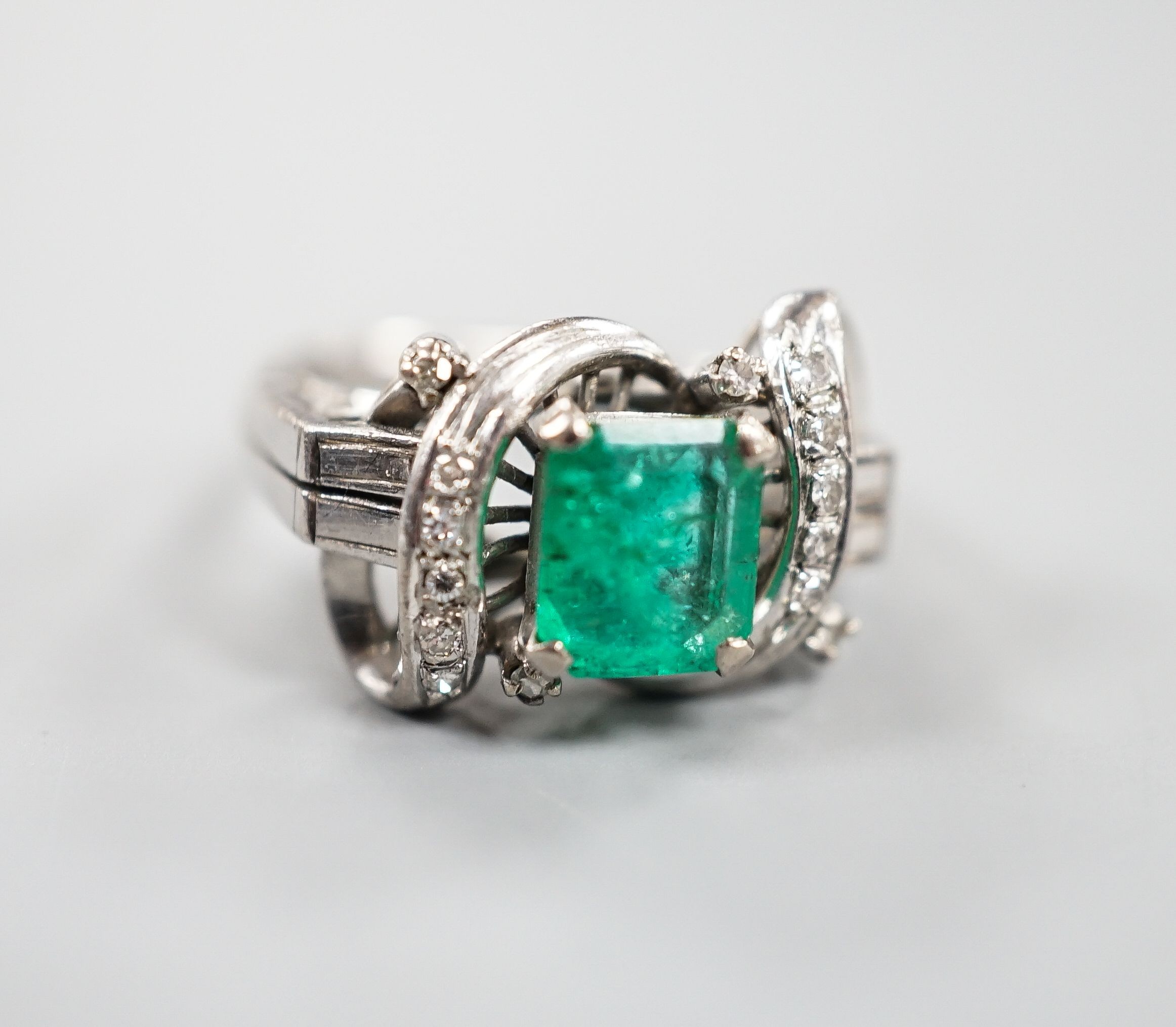 A modern 14k white metal and single stone emerald ring, with diamond chip set scroll setting, size K/L, gross weight 4.5 grams.
